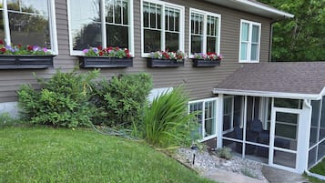 A residential house with a covered patio, flower boxes on the windows, and a well-maintained lawn.