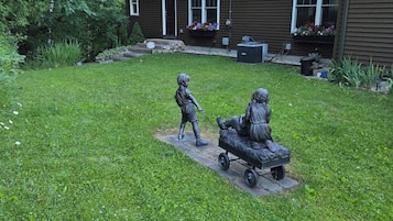 A grassy yard with a statue of a child and a horse-drawn cart.
