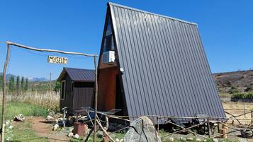A rustic cabin with a slanted roof, a wooden door, and a metal sign reading 'MYSELIM'.