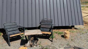 A metal building with two black chairs and a wooden table outside.