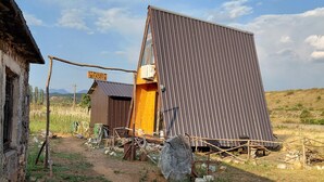 A rustic outdoor setting with a corrugated metal structure, a wooden building, and a dirt path.