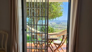 Une pièce dotée d’une porte-fenêtre coulissante donnant sur un espace extérieur aménagé avec un hamac, une table et des chaises.