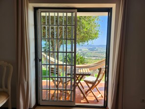 A room with a sliding glass door leading to an outdoor area with a hammock, a table, and chairs.