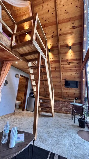 Ein Holzinnenraum mit Treppe, Essbereich und an der Wand montiertem Fernseher.