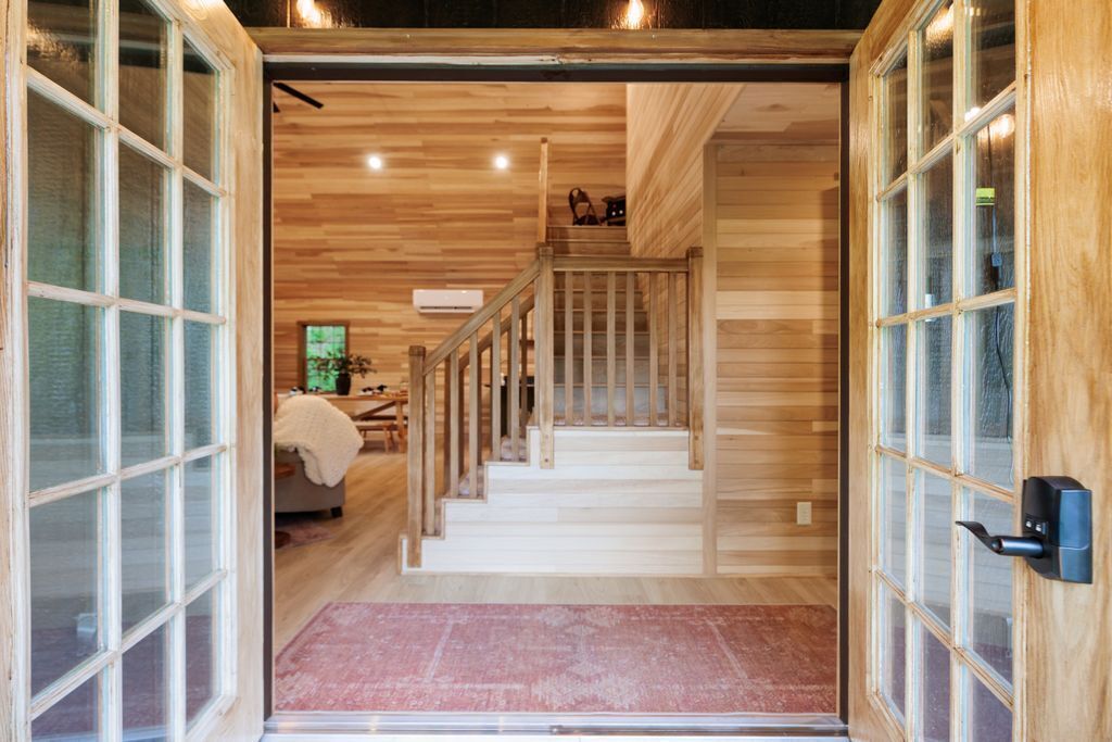 Un interior de madera con una escalera, una cama y un ventanal.