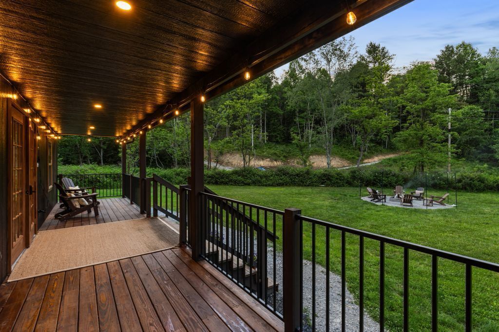 Une terrasse en bois avec une rambarde, des sièges d’extérieur et une vue sur une zone boisée.