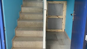 A staircase with a handrail, a wooden door frame, and a blue wall. - 2-Bedroom Apartment, Ocean View, Beach 50 m Away, Air Conditioning, Water Tank (Le Gosier)