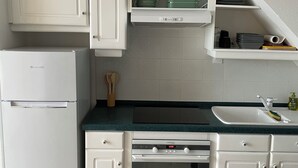A compact kitchen with white cabinets, a built-in oven, and a refrigerator. - 2-Bedroom Apartment, Ocean View, Beach 50 m Away, Air Conditioning, Water Tank (Le Gosier)