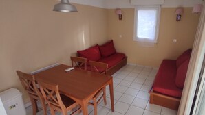 Ein Zimmer mit Esstisch, Stühlen, einer Couch, einem Fenster und einer Lampe.