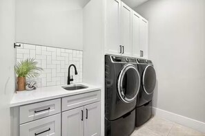 A laundry room with a washing machine, a sink, and cabinets. - 24 Guests l Private Pool/Spa l Mansion (Hurricane)
