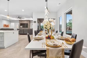 A modern dining area with a white table set for six, surrounded by dark chairs. - 24 Guests l Private Pool/Spa l Mansion (Hurricane)