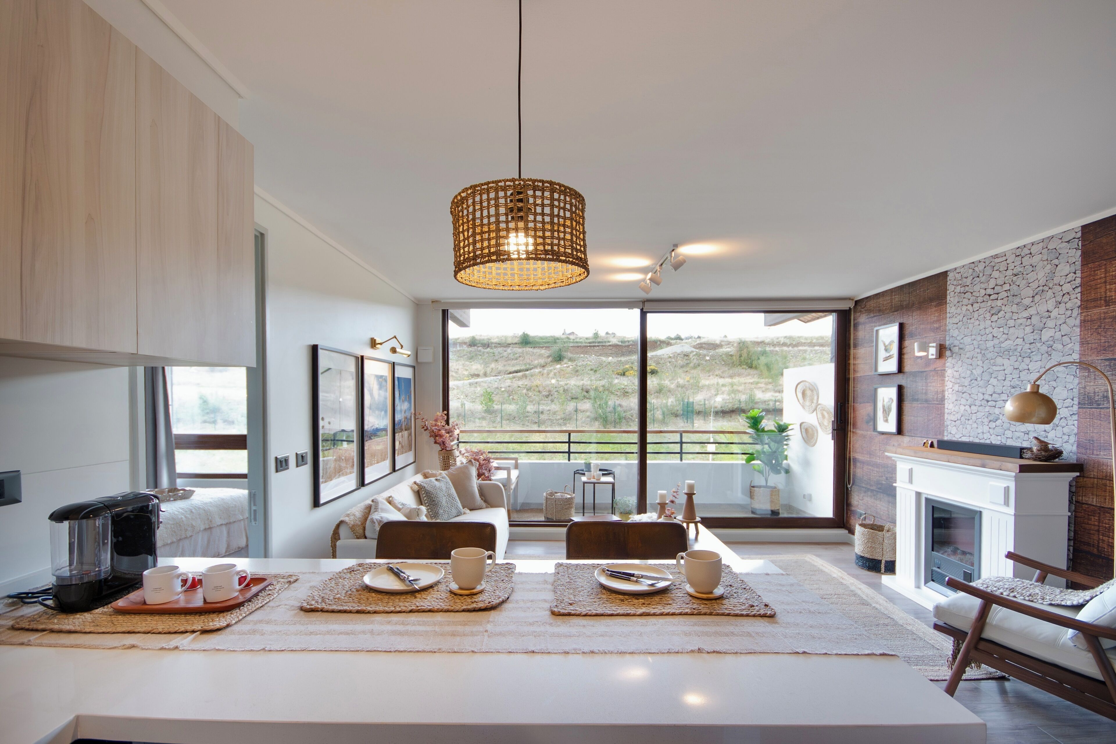 Een moderne woonkamer met een eethoek, grote ramen, een open haard en uitzicht op de omgeving.
