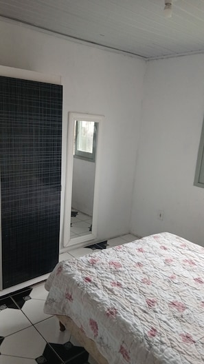 A bedroom with a bed, a window, and a door leading to a tiled area.