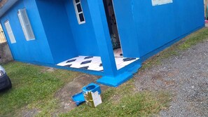 A blue building with a small window, a door, and a tiled entrance.