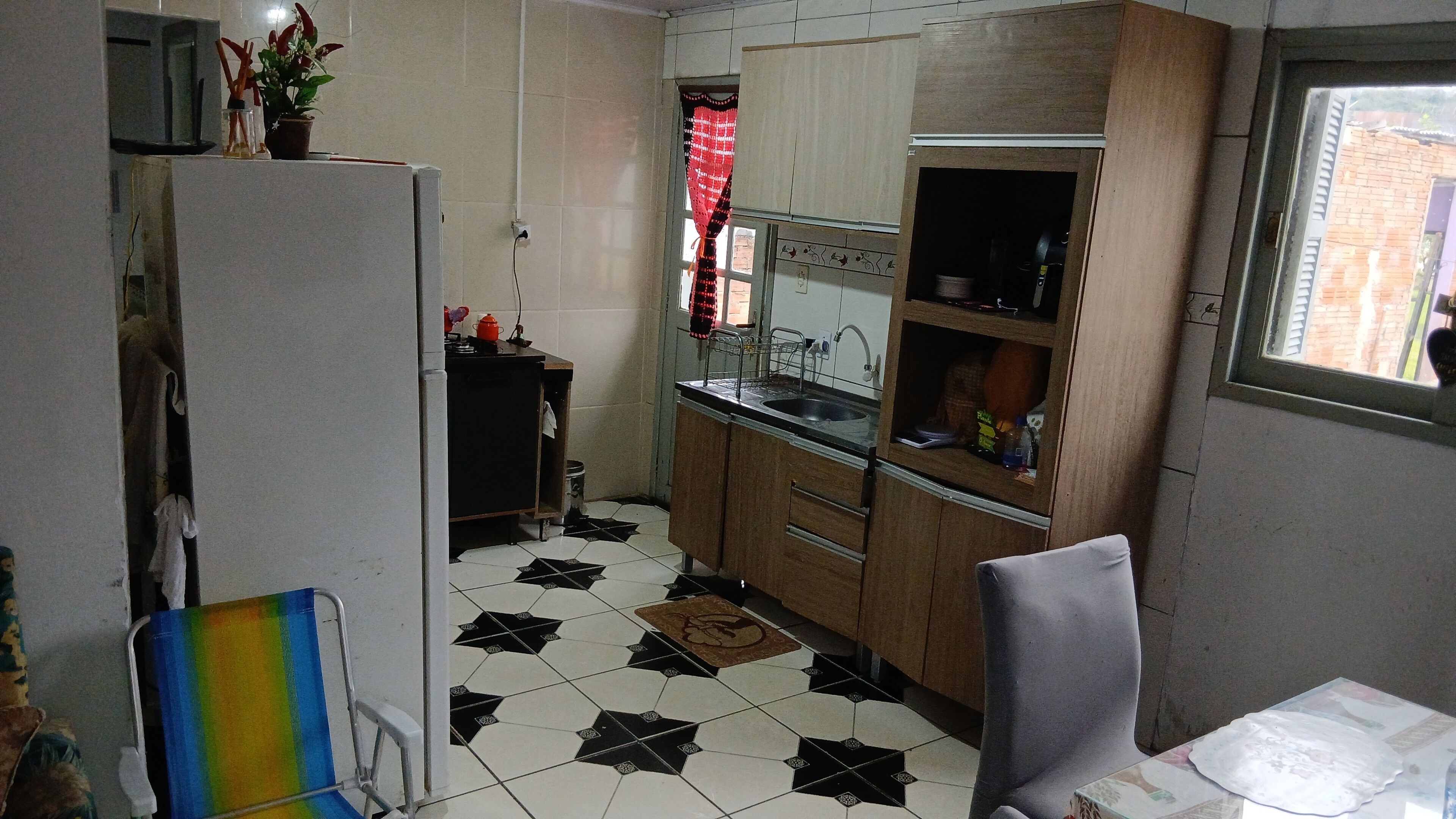 A compact kitchen with a refrigerator, sink, and wooden cabinets.