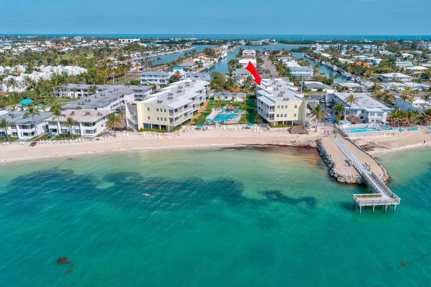 A coastal hotel with multiple buildings, a beach, and a pier.