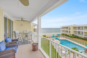 A balcony with wicker furniture, a ceiling fan, and a view of the ocean. - Island Breeze-Luxury Condo-Private Beach & Pool (Key Colony Beach)