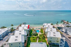 A resort with multiple buildings, a swimming pool, and a beach view. - Island Breeze-Luxury Condo-Private Beach & Pool (Key Colony Beach)