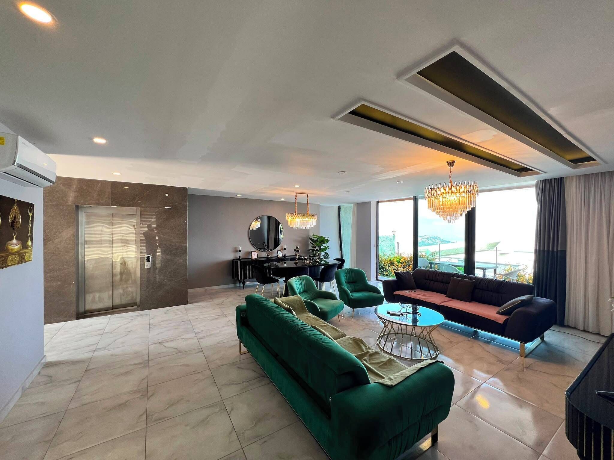 A modern living room with a green sofa, a round coffee table, and a chandelier.