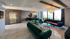 A modern living room with a green sofa, a round coffee table, and a chandelier.