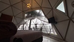 A geodesic dome room with a bed, a table, and a hanging light fixture. - FEYRE · Meraki Cabañas & Glamping by GEstores (Mineral del Chico)
