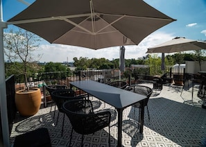 An outdoor patio with a table and chairs, surrounded by patterned flooring and umbrellas. - Zapopan Central Apt: Pet-Friendly, Near Basilica (Zapopan)