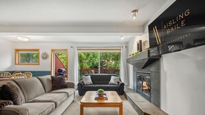 Ein modernes Wohnzimmer mit Kamin, einer Couch, einem Couchtisch und einem Essbereich mit Stühlen und einem Tisch.