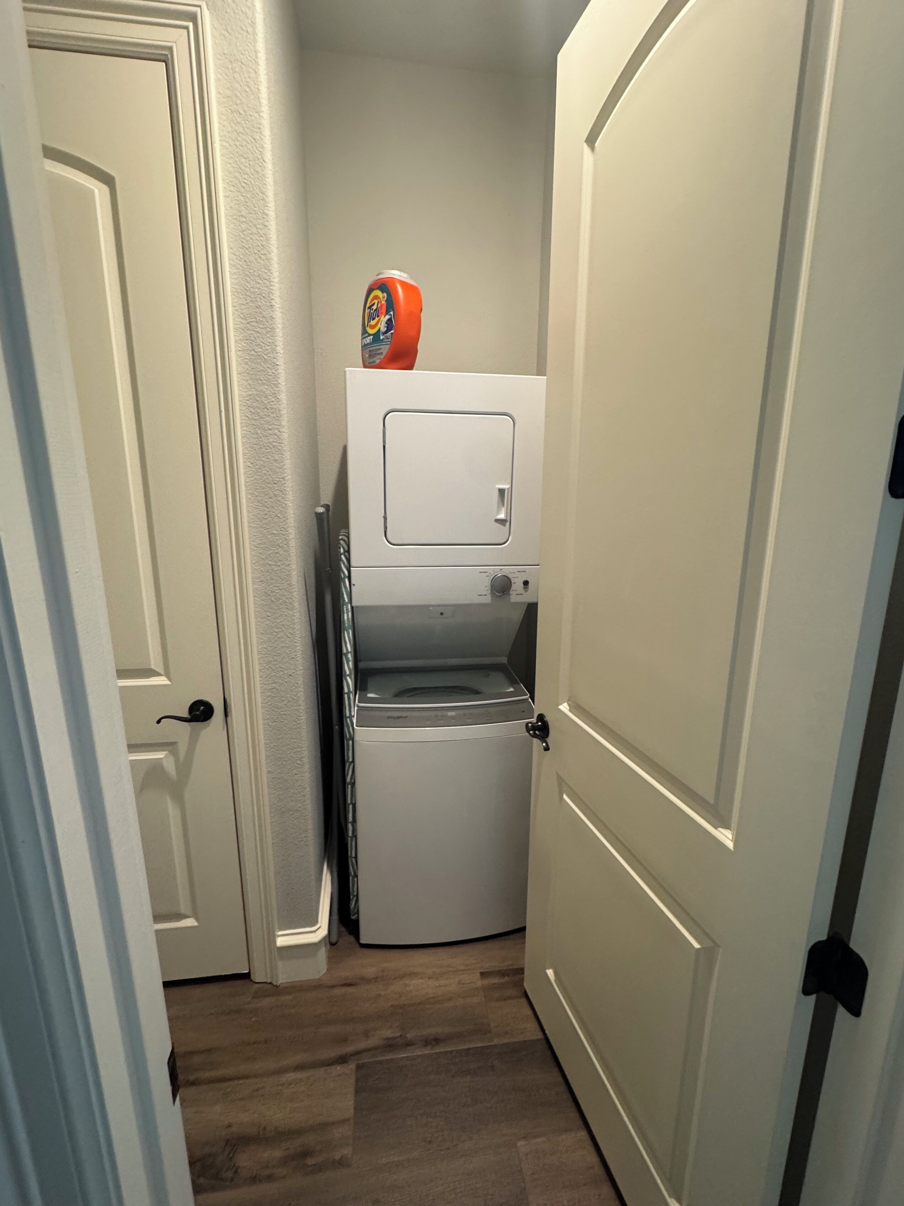 Une buanderie équipée d’un lave-linge et d’un sèche-linge superposés, d’une porte et d’un distributeur de lessive fixé au mur.