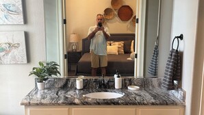 A bathroom with a marble vanity, a large mirror, and a ceiling light fixture. - Marr Building North Condo, Downtown Denison, Denison, Texas, Lake Texoma (Denison)