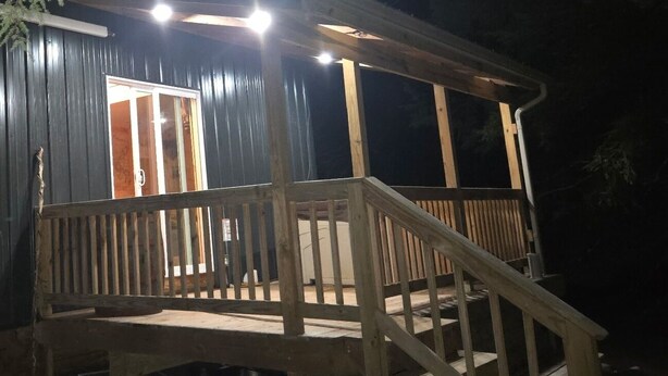 Uma cabana de madeira com varanda e escadaria que dá acesso à entrada.