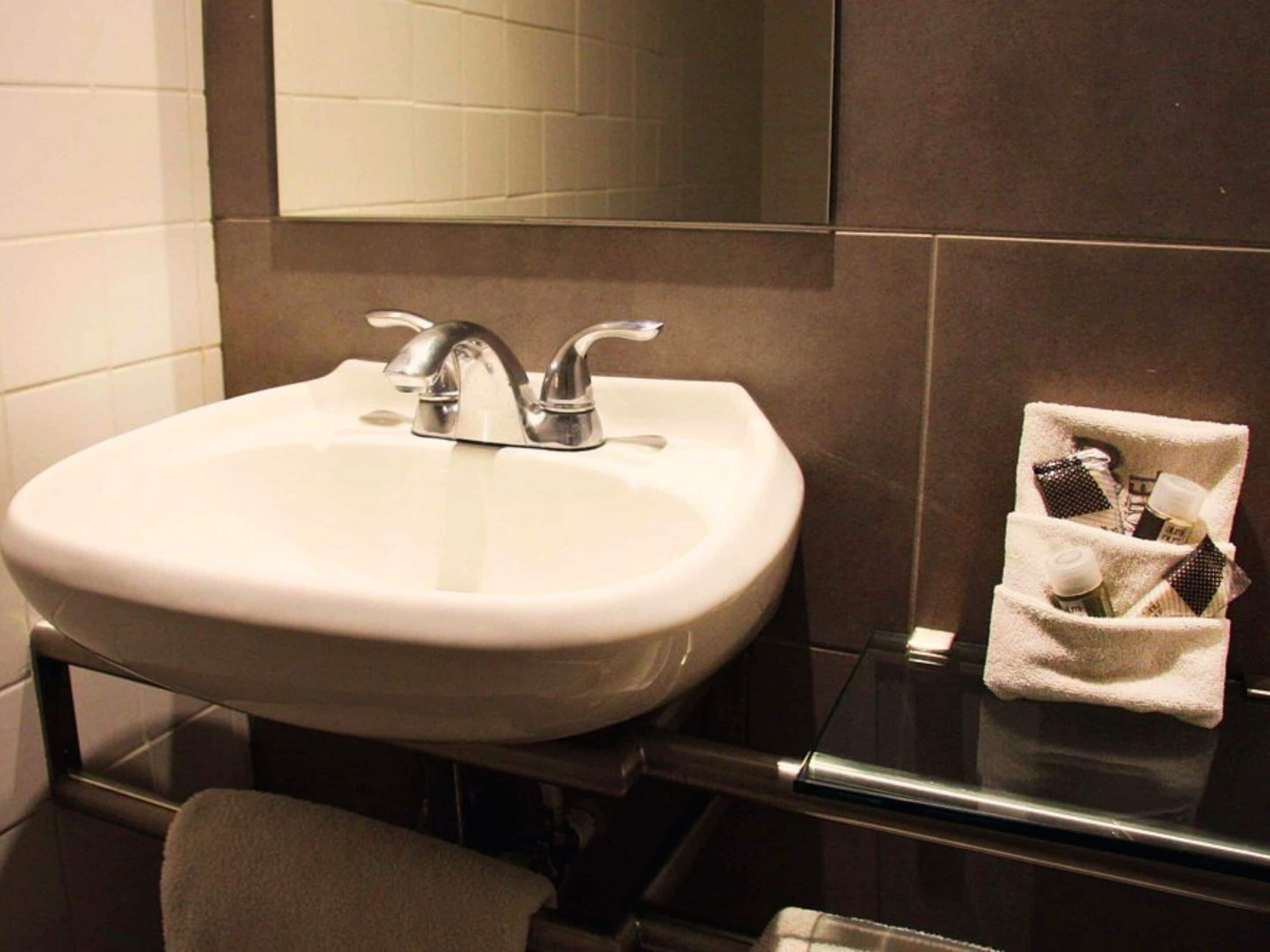 A bathroom with a white sink, a mirror above it, and a towel rack with a towel.