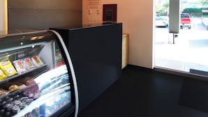Un interior moderno con una máquina expendedora, un panel negro y vistas a coches aparcados fuera.
