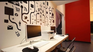 Un espacio de trabajo moderno con dos computadoras de escritorio, un teclado, un ratón y una impresora sobre una mesa grande.