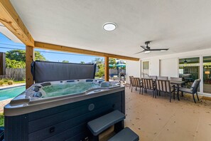 Un bain à remous avec des marches, un patio couvert et du mobilier d’extérieur.