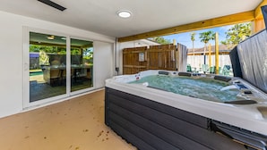 Ein Whirlpool in einer überdachten Außenbereich mit einer Schiebetür zu einer Terrasse.