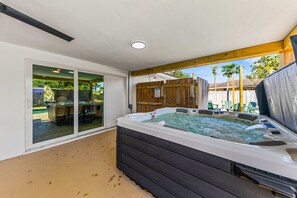 Ein Whirlpool in einer überdachten Außenbereich mit einer Schiebetür zu einer Terrasse.