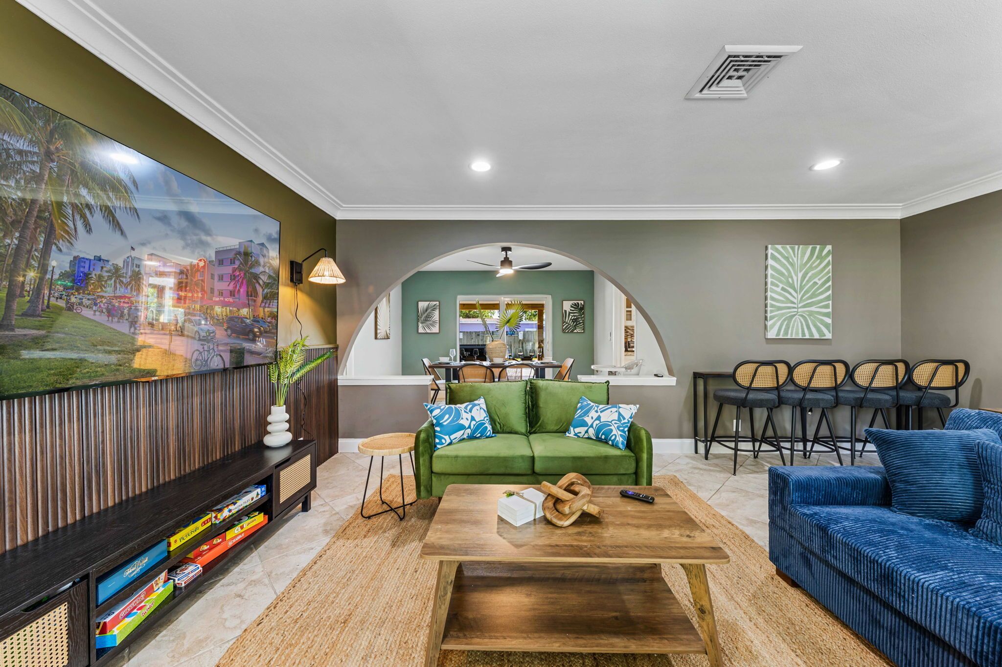 A living room with a green sofa, blue sofa, wooden coffee table, and a TV on a wooden stand.