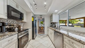 Eine moderne Küche mit Granit-Arbeitsplatten, Edelstahlgeräten und Blick ins Freie.