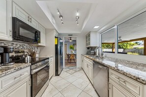 Eine moderne Küche mit Granit-Arbeitsplatten, Edelstahlgeräten und Blick ins Freie.