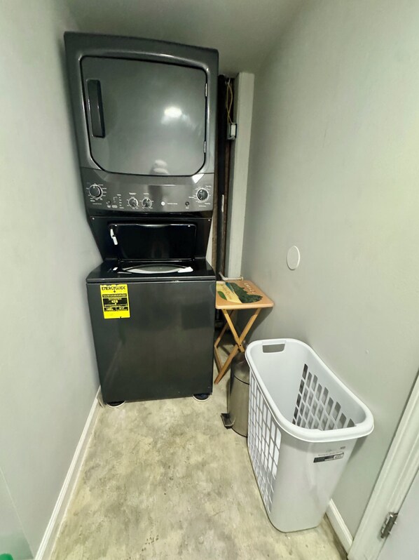 A compact laundry room with a washer, dryer, and a white laundry basket.