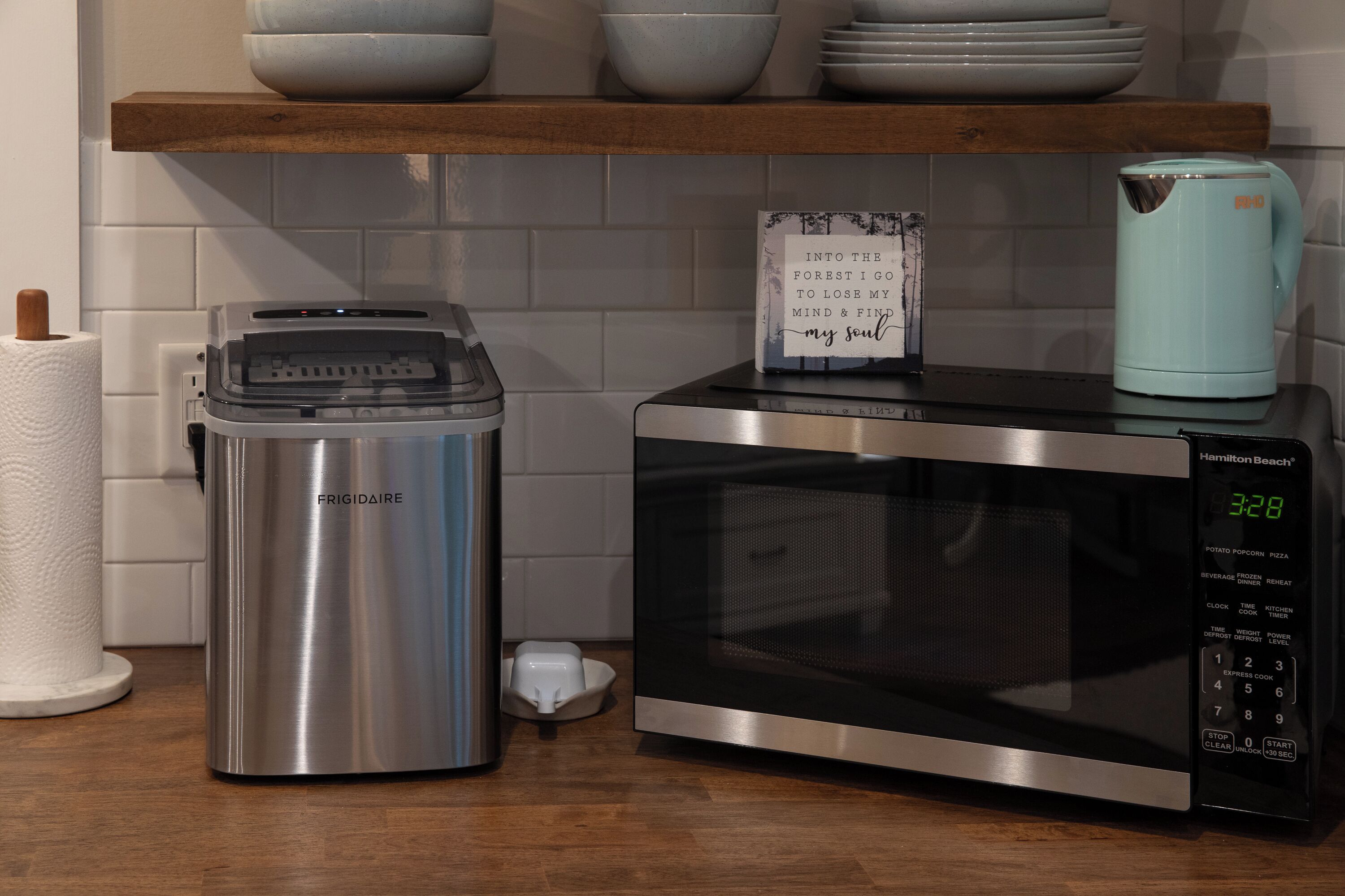 Et køkken med en Frigidaire kaffemaskine i rustfrit stål, en mikrobølgeovn og et skilt på mikrobølgeovnen.