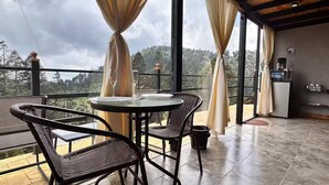 A balcony with a table and chairs, a coffee machine, and a view of the forest. - INARI · Meraki Cabañas & Glamping by GEstores (Mineral del Chico)