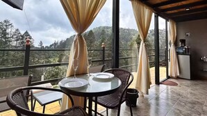 A balcony with a table and chairs, a kitchen area, and a view of a forested area. - INARI · Meraki Cabañas & Glamping by GEstores (Mineral del Chico)