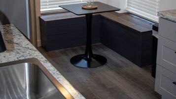 A compact kitchen with a built-in refrigerator, a sink, and a small table with a vase.