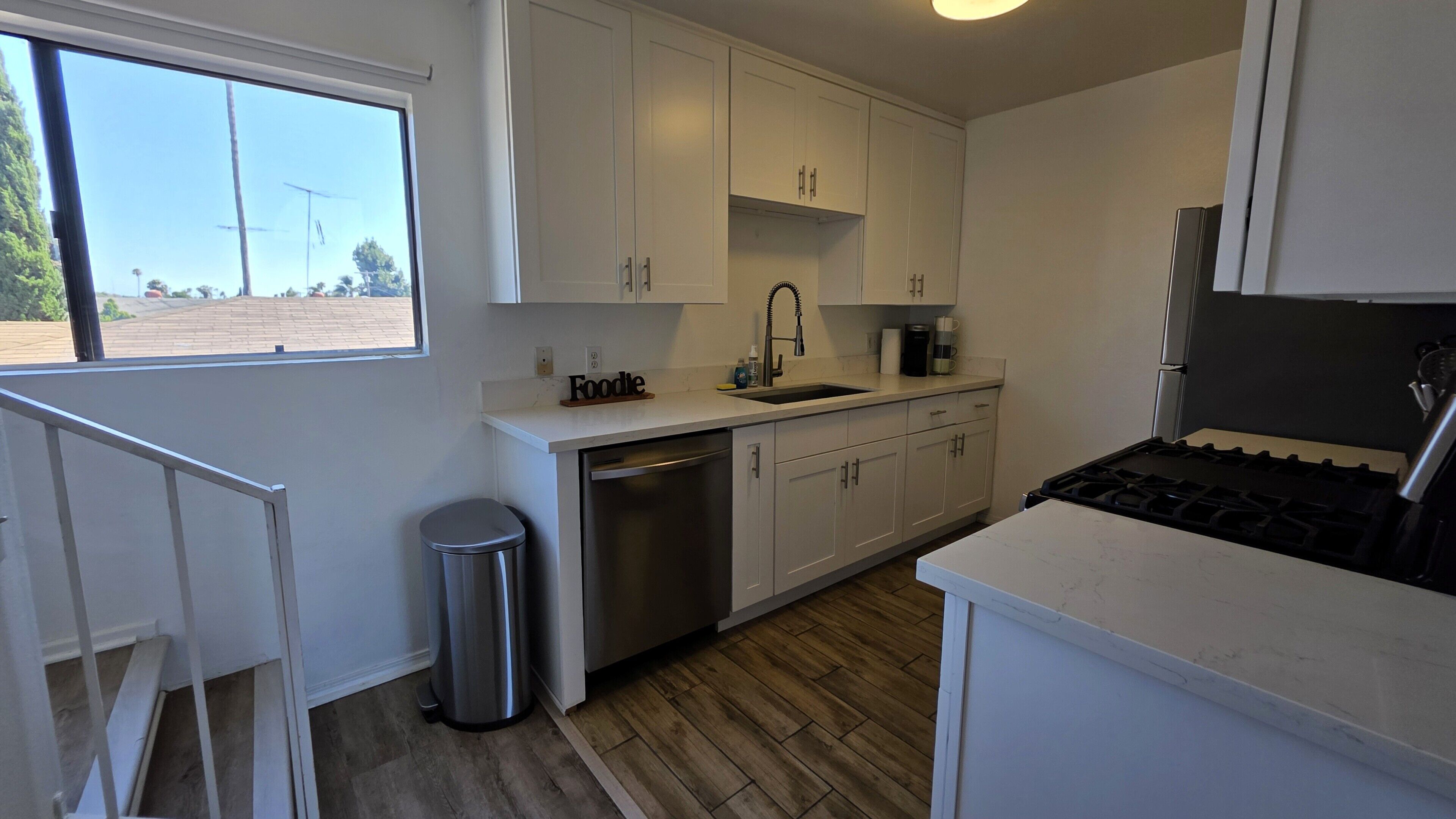 A modern kitchen with white cabinets, a stainless steel sink, and a gas stove.