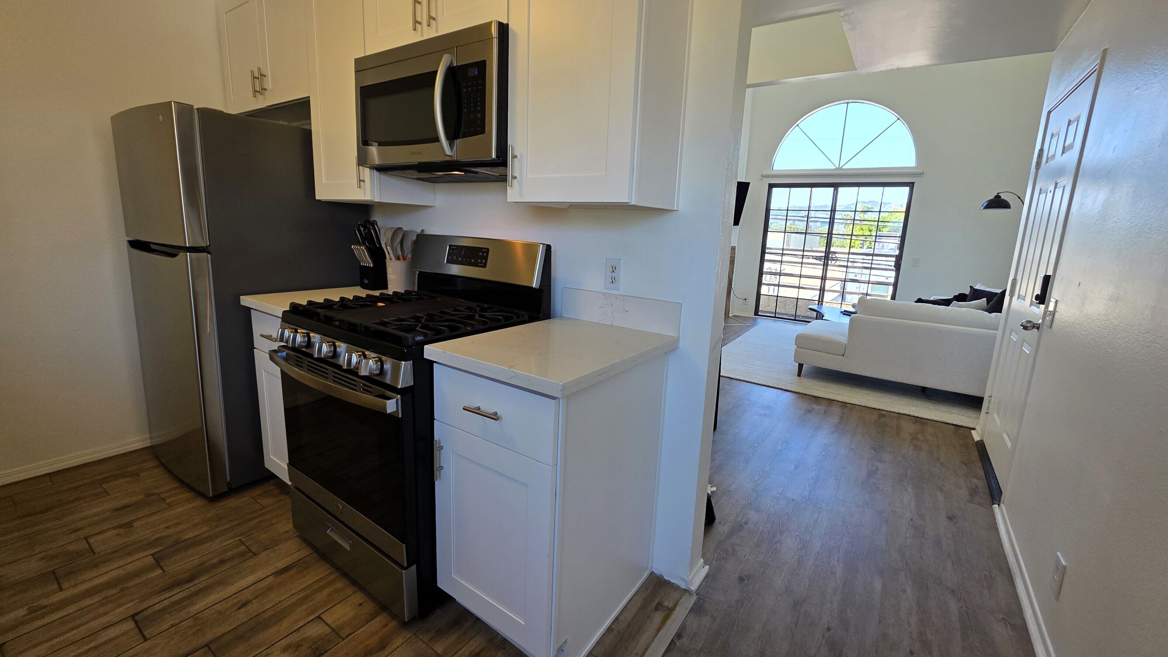 A compact kitchen with a stove, microwave, and refrigerator.