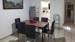 Ein Essbereich mit Tisch, Stühlen, einem Kühlschrank und einem Bild an der Wand.