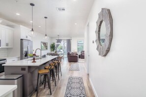 A modern kitchen with a central island, bar stools, and a dining area with a view.