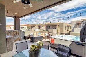 A rooftop terrace with outdoor seating, a hot tub, and a view of surrounding buildings.