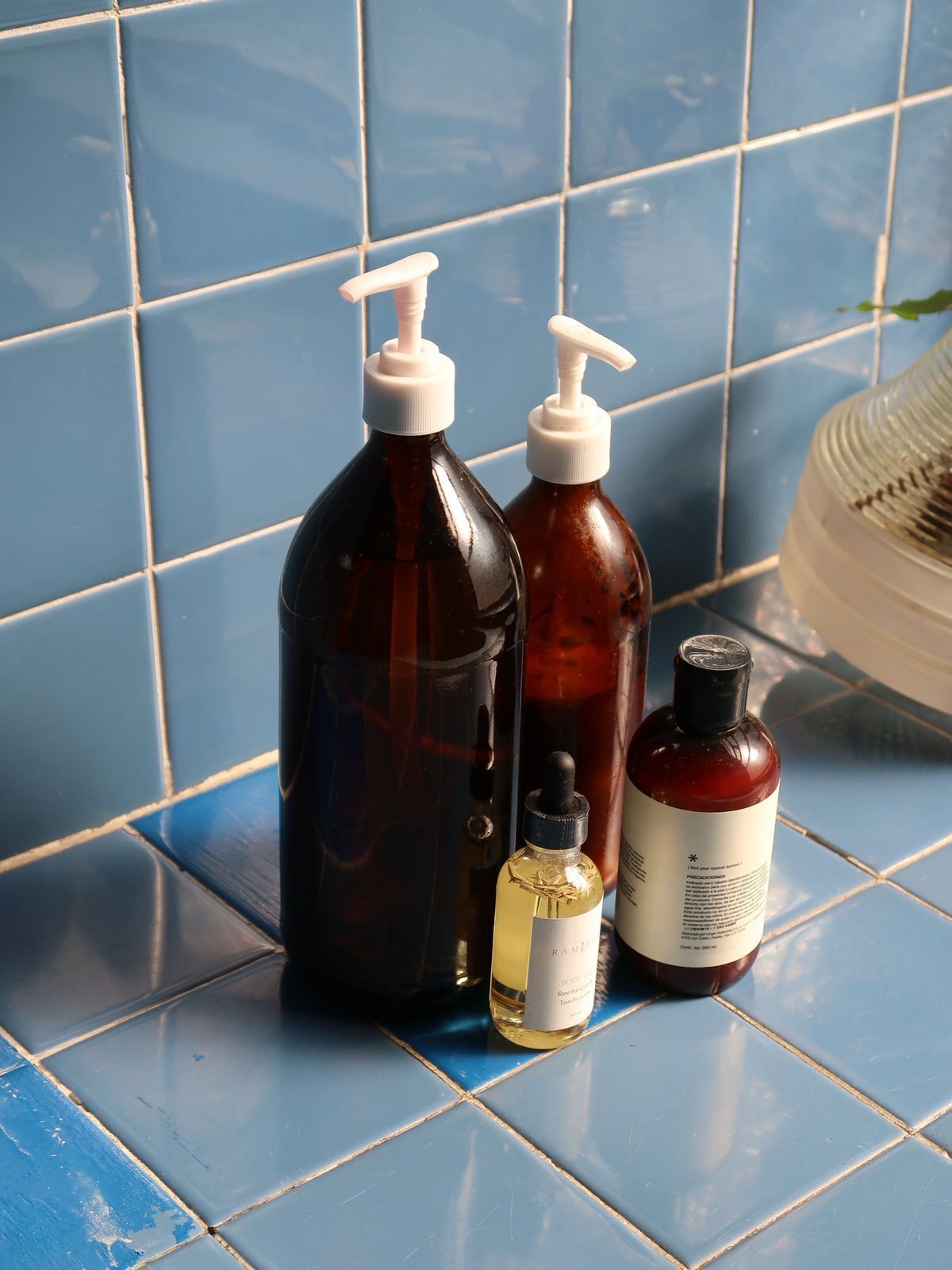 Three bottles of liquid on a tiled surface.